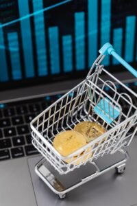 Mini shopping cart with bitcoins and laptop, symbolizing cryptocurrency investment and online trading.