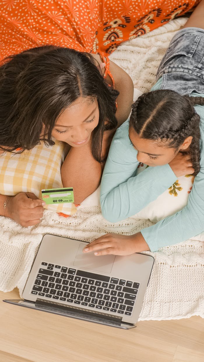 African American mother and daughter shopping online using a laptop in a cozy home setting.